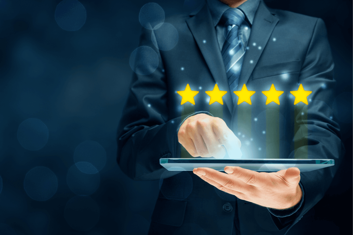 Supplier Rating System Business professional in a suit holding a tablet, using one hand to tap the screen. A five-start rating appears above the tablet.